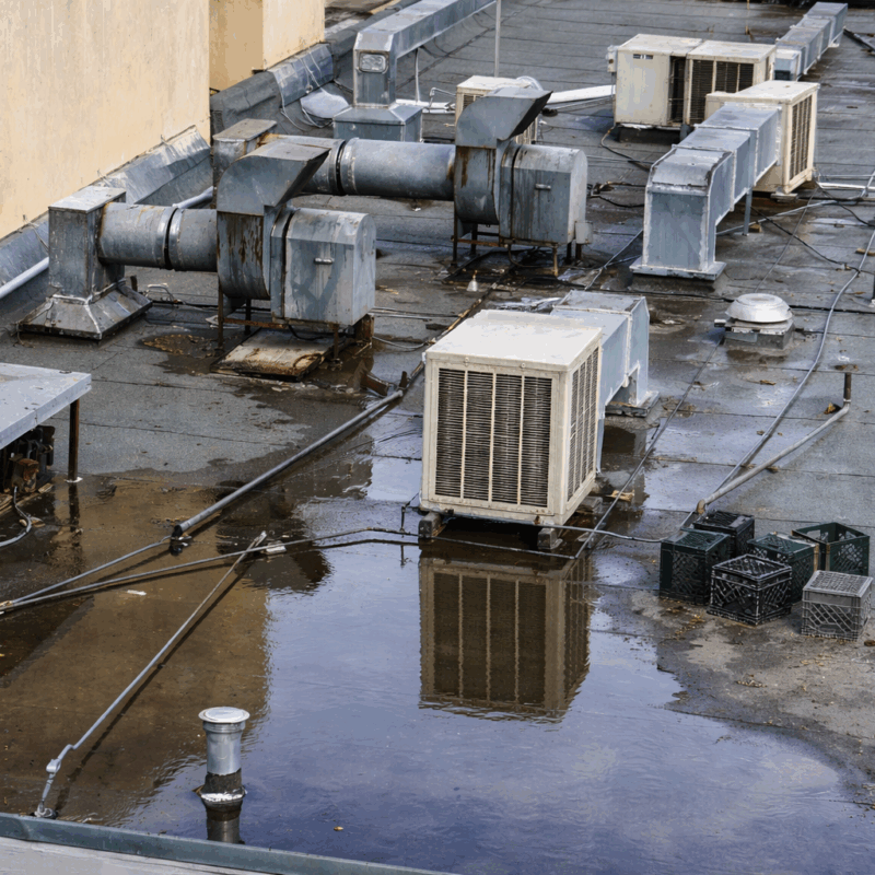 Ponding water on a flat commercial roof around HVAC units after winter rain in the Central Valley